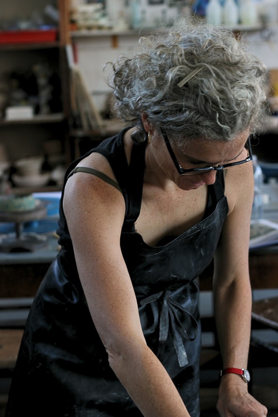 Older woman trying pottery for the first time in a bright studio